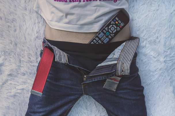 Homem deitado na cama e assistindo TV com o controle remoto da TV em suas cuecas
. - Foto, Imagem
