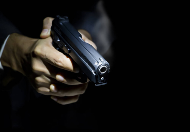 Close up male hand holding gun with dark background use for texts display - Photo, Image