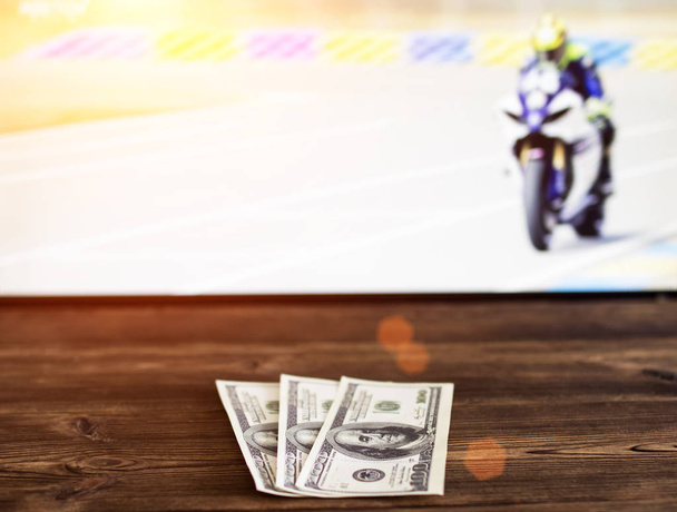 Money dollars on the background of the TV on which show motorcycle racing, sports betting, bookmaker - Fotó, kép