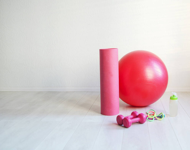 Sports equipment. Gym ball, yoga mat, skipping rope, dumbbell  and bottle of the water closeup on white background - Photo, Image