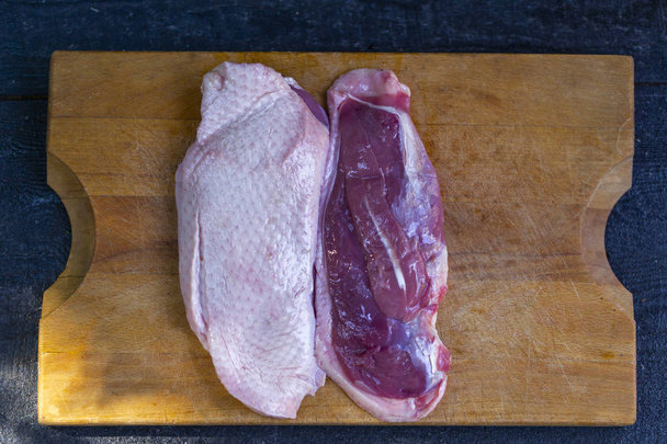 утиная грудь, свежее мясо утки на деревянной доске
 - Фото, изображение