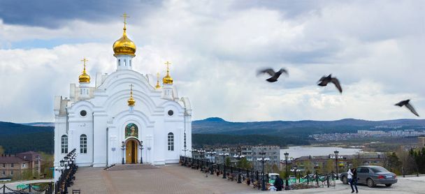 Templo de San Serafín de Sarov en Zlatoust en un día nublado. Iglesia cristiana. Las aves vuelan cerca. El río abajo en la distancia
. - Foto, imagen