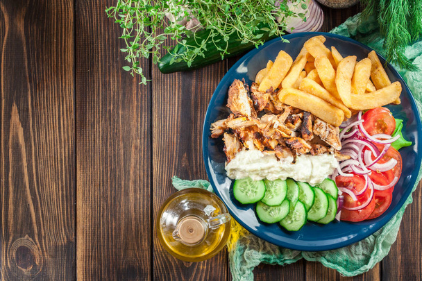 Görög gyros tál, hasábburgonyával, zöldségekkel. Tálalva tzatziki szósz - Fotó, kép