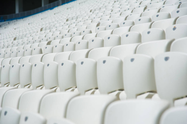Tribune of fans at the stadium. Empty white seats in stadium - 写真・画像