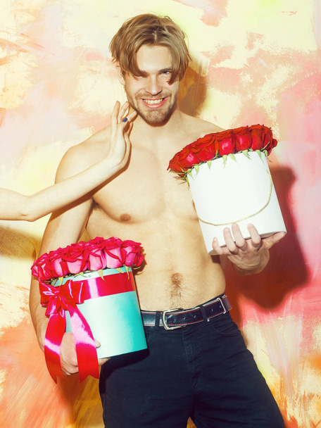 bearded muscular man with sexy body holds red rose box - Foto, Bild