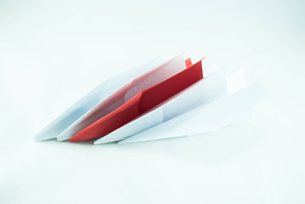 Red paper plane among white ones on a white background, isolated. Concept (idea) of airlines, freedom, leadership, success, and individualism. - Photo, Image