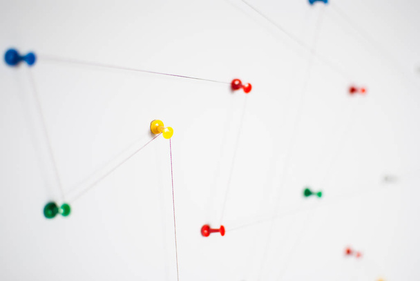 背景。ネットワーク、ソーシャル メディア、インターネット、チームワーク、コミュニケーション抽象の抽象的な概念 (考え方)。カラフルなピンは、赤い糸で一緒にリンクされています。分離されました。関連のある団体. - 写真・画像