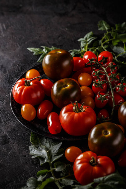 Close up of ripe tomatoes on black grunge background - Foto, afbeelding