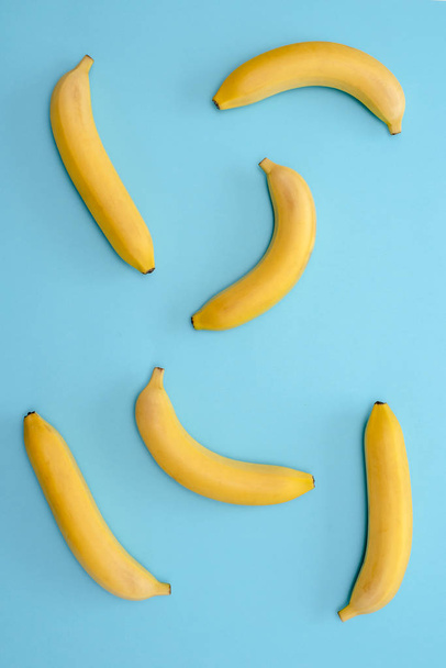 Fondo plátanos maduros dispersos aleatoriamente en la superficie azul
 - Foto, Imagen