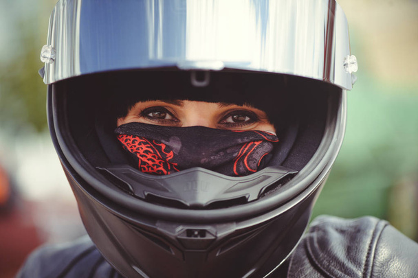 woman biker covers her face with a handkerchief and wears a helmet, safety on the road, close-up. - Photo, Image