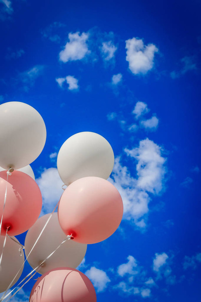 White pink balloons against the sky. Sunny weather and sky with clouds - Фото, зображення