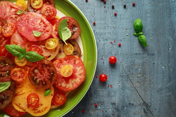 Kleurrijke tomatensalade met heirloom, peer vormig, rundvlees hart, tigerella, brandywine, kers, zwarte tomaten in een groene plaat. gezonde voeding - Foto, afbeelding