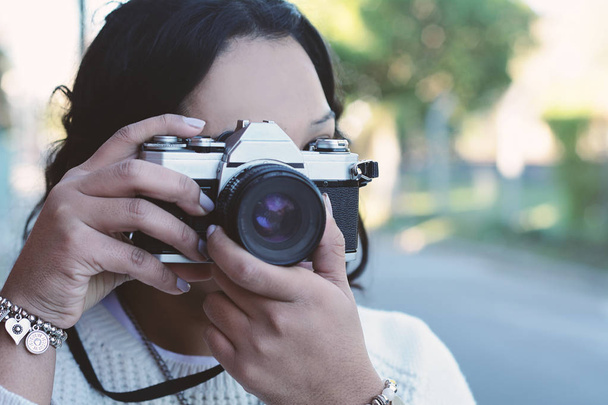 portrait of young woman having fun taking photos with retro film camera. Outdoor lifestyle portrait. - Фото, зображення