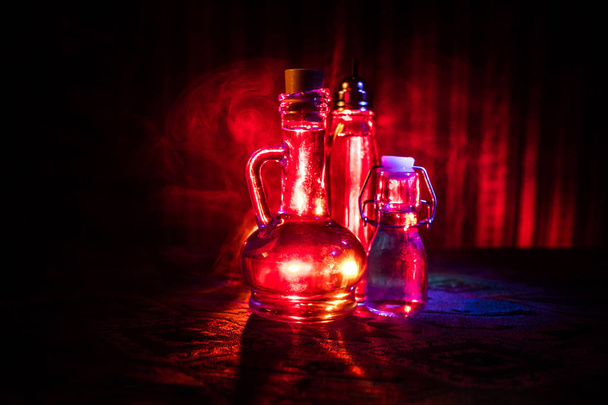 Garrafas de vidro antigas e vintage no fundo nebuloso escuro com luz. Conceito de veneno ou líquido mágico
. - Foto, Imagem