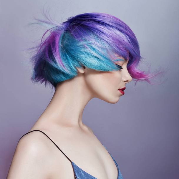 Portrait of a woman with bright colored flying hair, all shades of purple. Hair coloring, beautiful lips and makeup. Hair fluttering in the wind. Sexy girl with short hair - Photo, image