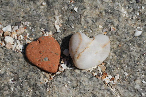 Twee stenen in de vorm van harten liggend op grote grijze steen. Closeup       - Foto, afbeelding