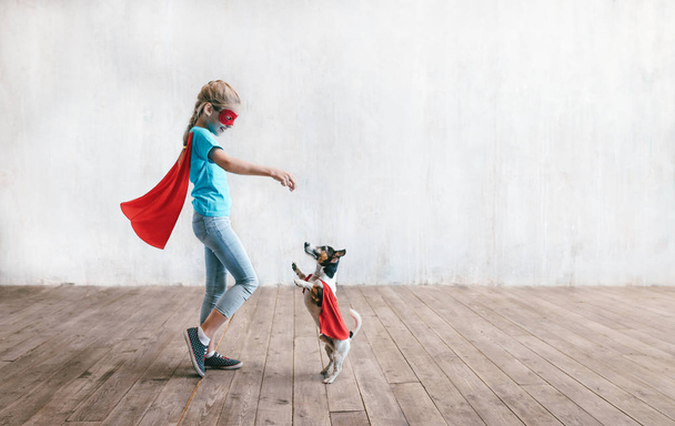 Little super girl with a dog in studio - Photo, Image