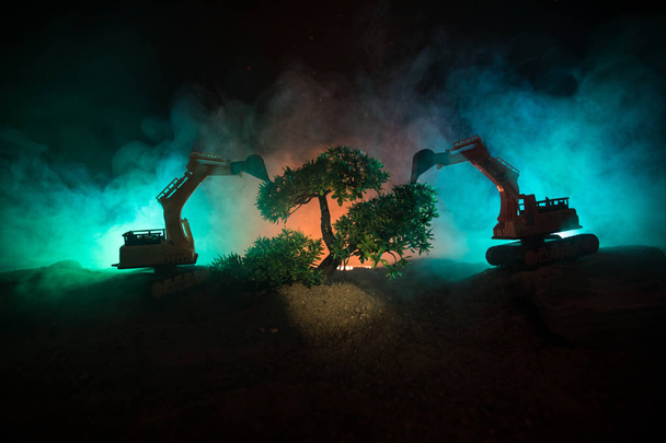 Deforestation of forest. Excavator used to dig up tree-stumps and roots after the forest was removed. Dark toned with fog table decoration. Conceptual. Selective focus - Photo, Image