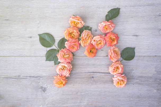 letter M of rose flowers on gray wooden background - Fotografie, Obrázek