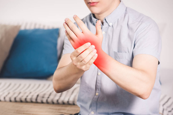 Pain in hand, man suffering from carpal tunnel syndrome at home, painful area highlighted in red - Fotografie, Obrázek
