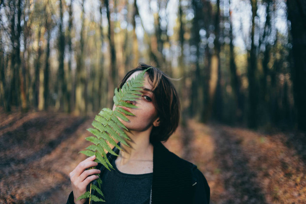 stylish hipster girl with fern bushes, among fern leaves in forest creative portrait of woman traveler atmospheric moment - Photo, Image