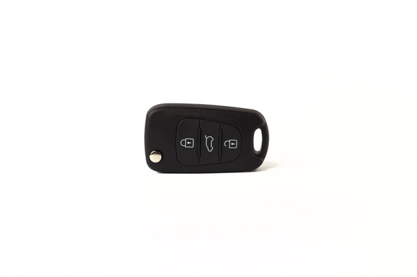 Black key ring with car key with remote control over white background. - Photo, Image