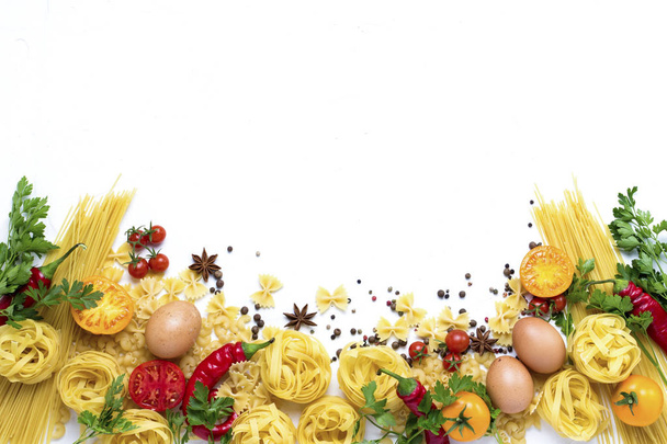 Włoski makaron różnego rodzaju z czerwonej papryki, jaja kurze, przyprawy, żółte i czerwone pomidory na białym tle kamienia. Koncepcja gotowanie włoskiego makaronu i sosu. Widok płaski świeckich, top. - Zdjęcie, obraz