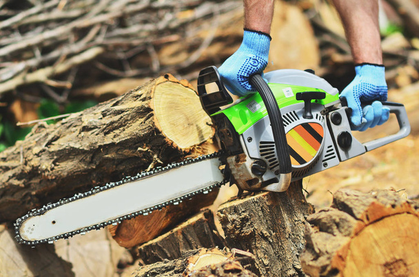 A man runs a chainsaw, removes a piece of wood - Foto, immagini