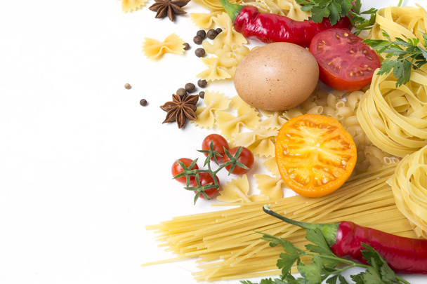 Ιταλικά ζυμαρικά διαφορετικού είδους με κόκκινη καυτερή πιπεριά, κοτόπουλο αυγά, μπαχαρικά, κίτρινες και κόκκινες ντομάτες σε λευκό φόντο πέτρα. Έννοια μαγειρική ιταλικά ζυμαρικά και τη σάλτσα. Επίπεδη lay, κορυφαία προβολή. - Φωτογραφία, εικόνα