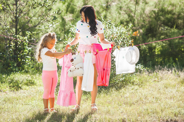 Söpö pieni tyttö ja hänen äitinsä ripustaa pyykkiä
 - Valokuva, kuva