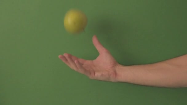 Caucasian male hand Bouncing a green apple on a green background. - Imágenes, Vídeo
