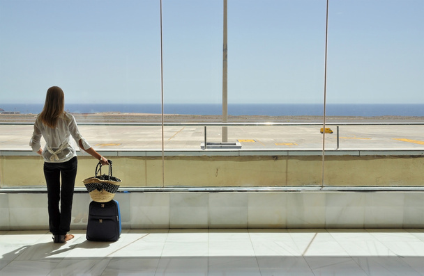 Fille à la fenêtre de l'aéroport regardant vers l'océan - Photo, image