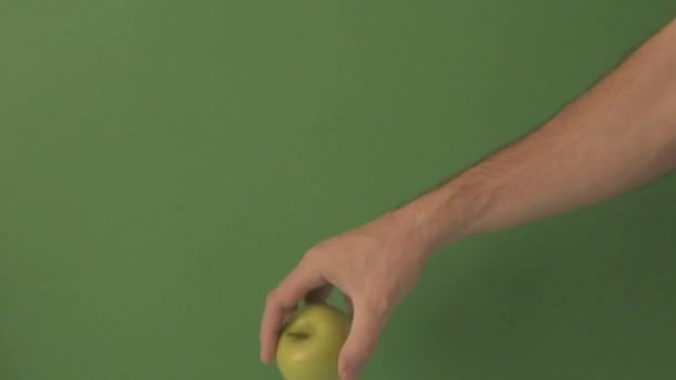 Caucasian male hand Bouncing a green apple on a green background. - Felvétel, videó