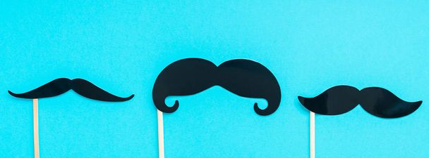 Creative long wide banner top view retro stylish black paper photo booth props moustaches turquoise background copy space. Men health awareness month fathers day masculinity concept blog social media - Foto, Imagem