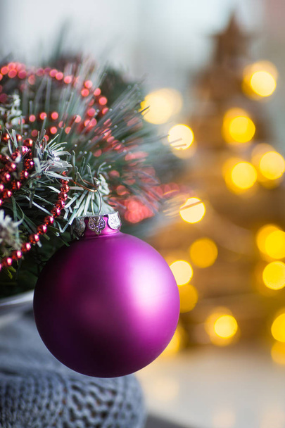 Nahaufnahme Karminrote Weihnachtskugel auf Tannenzweig mit warmen Bokeh-Lichtern im Hintergrund. Neujahrskarte. - Foto, Bild