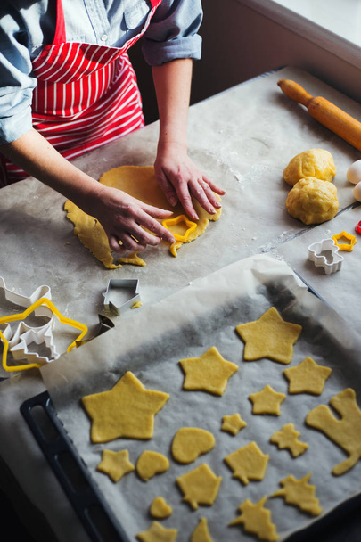 Mani femminili in farina che fanno il biscotto di Natale nella forma di stella da pasta in luce del giorno. Processo di cottura a casa
 - Foto, immagini
