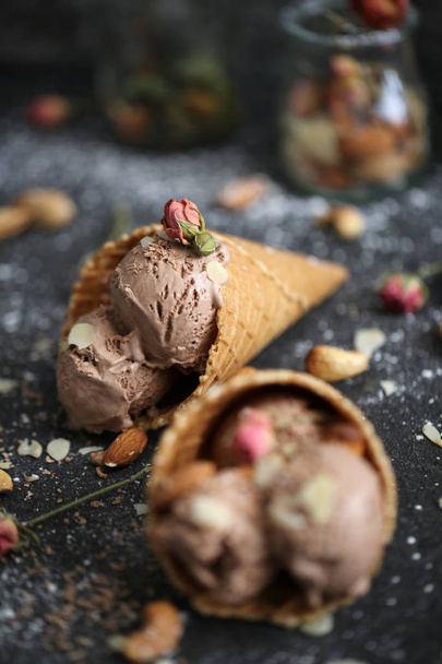 Pěkný designigned čokolády zmrzlina na tabulka s ořechy a cukr pund a růží v poháru vafle na tmavém pozadí - Fotografie, Obrázek