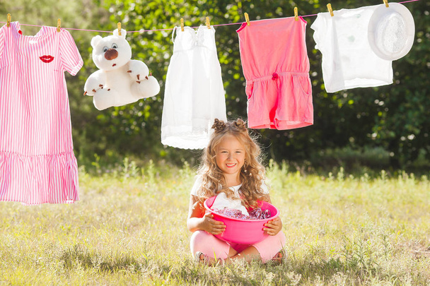 Söpö pieni tyttö ripustaa pyykkiä ulkona
 - Valokuva, kuva