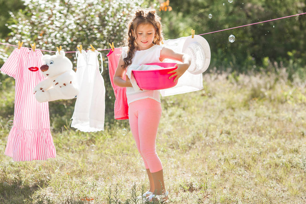 Ładna dziewczynka wieszanie prania na zewnątrz - Zdjęcie, obraz