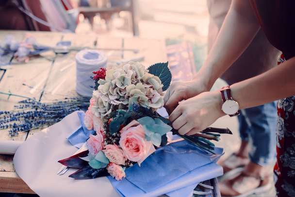 Woman is crafting rose flower bouquet on the wooden table - 写真・画像