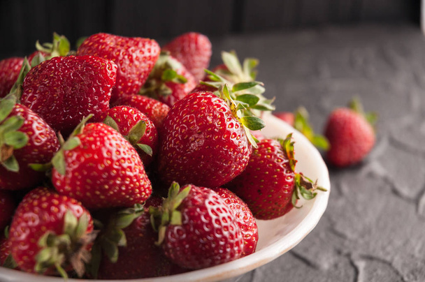 frische Erdbeeren auf einem Teller auf schwarzem Hintergrund - Foto, Bild
