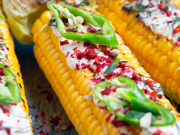 Grilled corn with cream sauce, spices, jalapeno on the blue boards. Close-up. - Photo, Image
