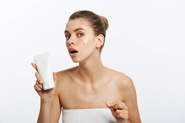 Beauty Youth Skin Care Concept - Beautiful Caucasian Woman Face Portrait tenant et présentant un produit en tube crème. Beau modèle Spa Fille
. - Photo, image