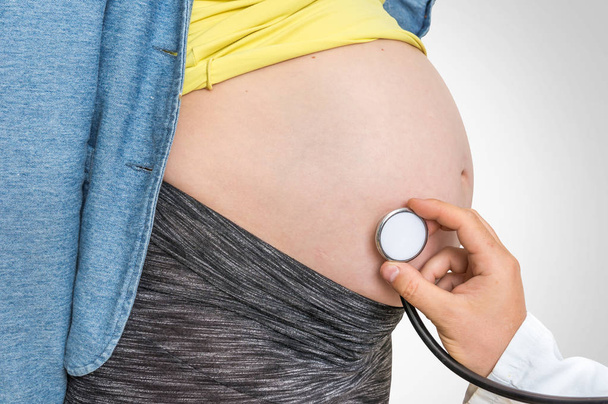 Pediatrician doctor with stethoscope is listening to heartbeat baby of pregnant woman - pregnancy concept - Photo, Image