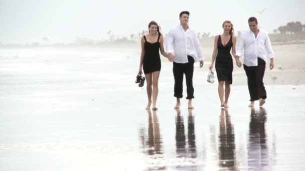 Cuatro jóvenes amigos atractivos disfrutando de la playa temprano en la mañana después de una noche social
 - Imágenes, Vídeo