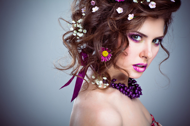 Jeune belle femme avec des fleurs dans ses cheveux et un maquillage lumineux
 - Photo, image
