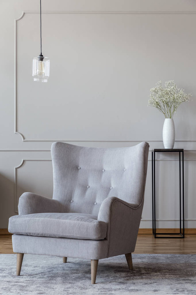 Light gray, elegant armchair and a black vase standing in a sophisticated living room interior with molding on beige walls - Φωτογραφία, εικόνα
