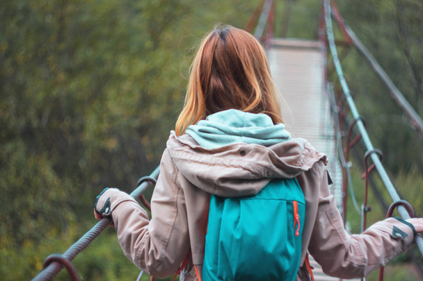 Orman asma köprü üzerinde kırmızı uzun saçlı kız gezgin  - Fotoğraf, Görsel