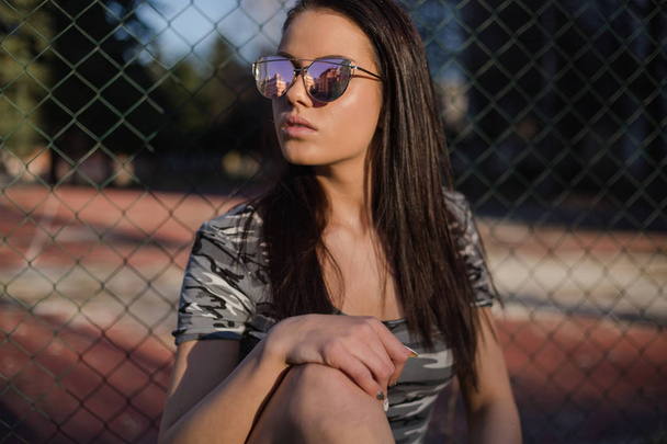 Élégante jeune femme en lunettes de soleil posant à l'extérieur
 - Photo, image