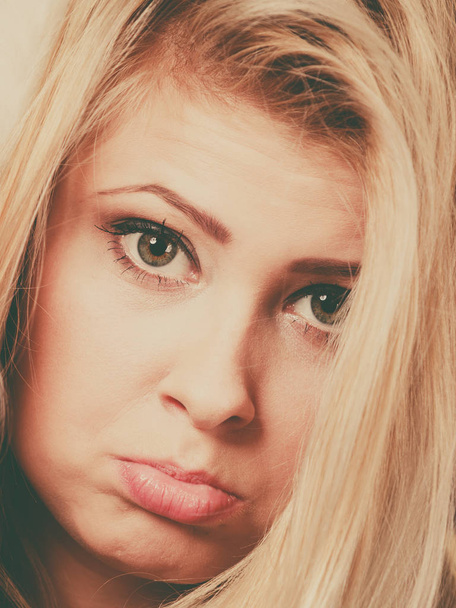 Close up of sad blonde young woman face, having cute gloomy expression. - Foto, afbeelding